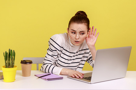 无意中听到女性握着近耳朵的手臂 试图在笔记本电脑坏互联网连接上的视频电话中听到秘密谈话背景