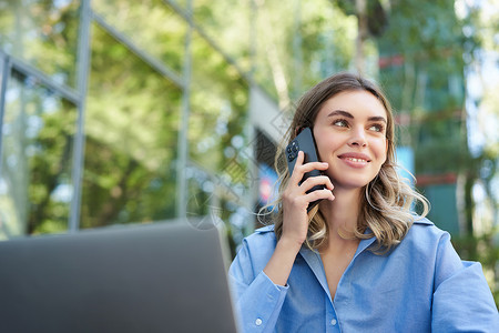 年轻女商务人士坐在公园外面 用笔记本电脑谈手机的画像 年轻女性 学生在户外工作 打电话 打电话雇主金融公司女士企业家电话营销员工成功的高清图片素材