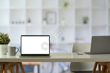 白色办公桌台的笔记本电脑前视 咖啡杯和陶瓷厂 广告设计空白屏屏障背景