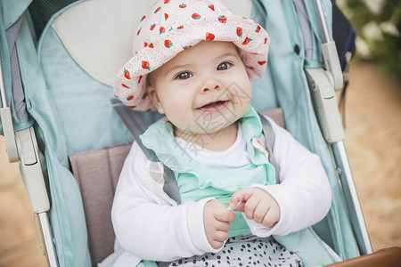 宝宝缺锌坐在一辆蓝色的婴儿车里 不牙不牙地笑着坐着背景
