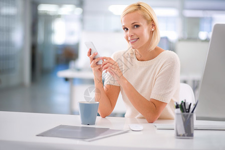 保持连接很容易 一个商务人士在办公桌用她的手机做客背景图片