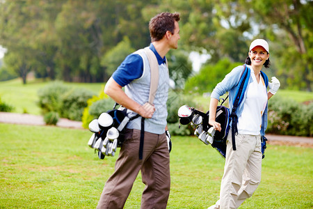 手草夫妇携带高尔夫球袋 夫妇背着高尔夫球袋 看着对方背景
