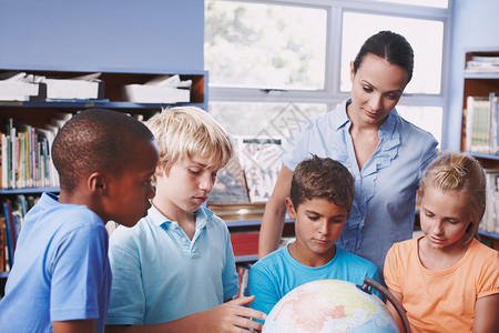 掌握地理知识 一位漂亮的年轻地理老师使用地球仪教她的学生了解世界背景图片