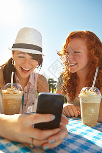 两个少女在用手机发短信时 享受着冰淇淋的甜言蜜语背景