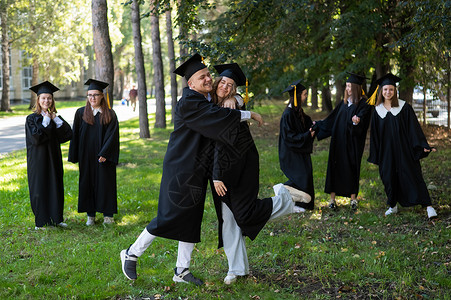一群穿着长袍的毕业生祝贺对方在户外毕业 笑声朋友们学校女性女孩校园大学学习证书友谊乐趣快乐的高清图片素材