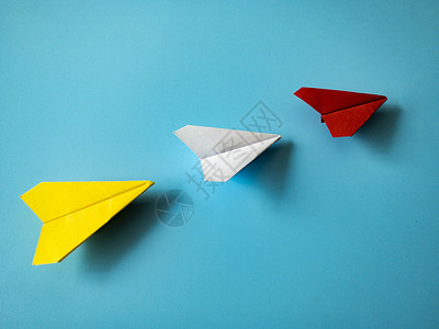 黄色折纸箭头红纸飞机折纸制成的白和黄色飞机 蓝背景 有可定制的文字空间 领导才能概念 笑声员工追随者进步创造力创新箭头成就动机生长技巧背景