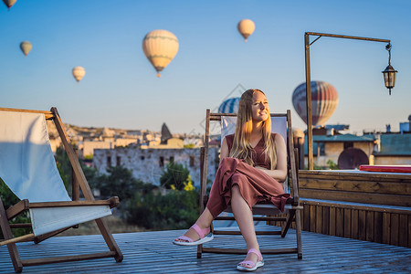 坐热气球的女孩在土耳其卡帕多细亚看热气球的女游客 土耳其概念中的快乐旅行 山顶上的女人享受美妙的景色岩石日出旅游吸引力天空公园航班悬崖蜜月远足背景