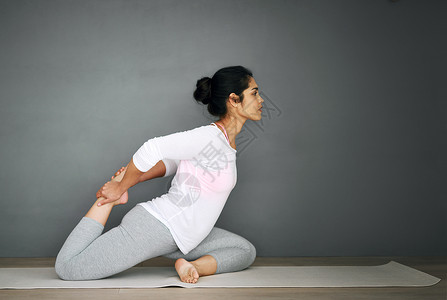 一个年轻女子在做瑜伽时 伸展着腰部的筋疲力尽高清图片