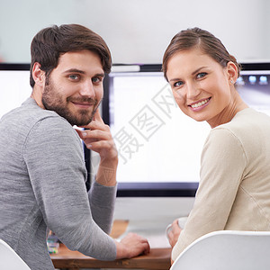 多活跃的二人组合啊 两个微笑的年轻专业人士在办公桌上的肖像背景图片