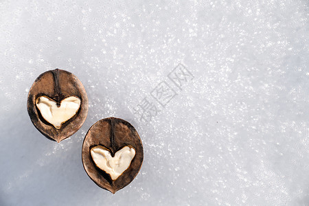 在白雪背景下由核桃半分制成的两颗白色心 爱情的概念 复制空间背景图片