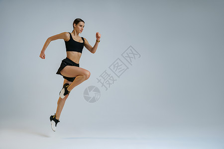 坚定的体育女运动员在中空中锻炼时因工作室背景而进行心操锻炼有氧运动动机成人运动活力赛跑者运动装女士短跑训练背景图片