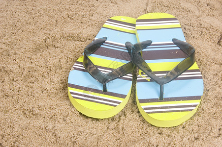 躺在沙滩上的绿色夏季拖鞋背景图片