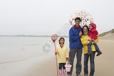 伞桶在海滩上快乐的一家人 带着雨伞在沙滩上 冒充背景