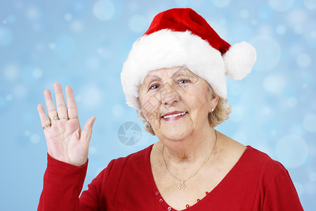 圣诞帽子奶奶挥舞着蓝色高清图片