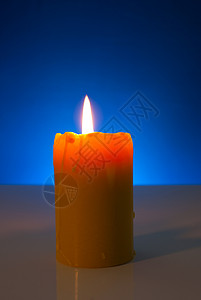 在蓝色背景下烧黄蜡烛; 火焰 黄色的 假期 圣诞节背景图片
