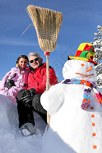父亲和女儿站在雪人旁边 冬天 玩具 冰 滚雪球 快乐背景图片