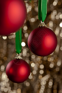 三个红色的圣诞胸围 在金亮闪闪发光的背腹前 闪亮的 玩具背景图片