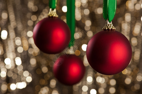 三个红色的圣诞胸围 在金亮闪闪发光的背腹前 闪亮的 玉乐背景图片