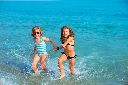 女孩朋友在海滩上一起跑来跑去的 湿的 夏天 海浪背景