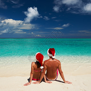 在马尔代夫海滩上穿着圣诞老人帽子的夫妇 热带背景图片
