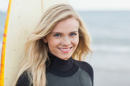 一个带着冲浪板的笑着美丽的女人的肖像背景图片