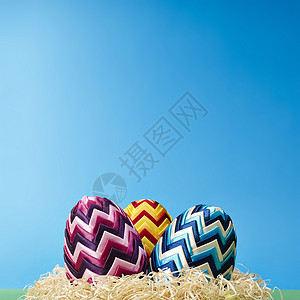 复活节鸡蛋在干草中 华丽的 红色的 闪亮的 蓝色背景 丝带背景图片