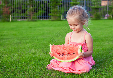 小女孩 拿着大西瓜 大块西瓜手握着绿草 微笑背景图片