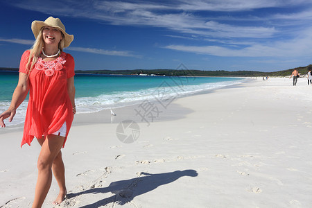 海姆斯海滩在美丽的沙滩上走着快乐的 微笑的女士背景