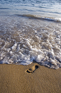 在海沙沙滩和海浪上单脚踏足背景图片