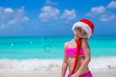 热带海滩上的红色圣诞礼帽的小可爱女孩 童年背景图片