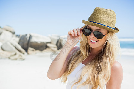 时尚的金发金发女郎在沙滩上对着摄影机微笑 美丽的 支撑图片