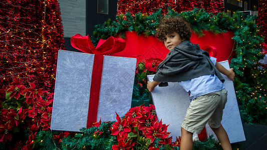 男孩试图握住圣诞礼物盒背景图片