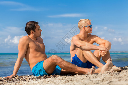 两个英俊的年轻人在海滩上聊天 航海的 情谊 坐着背景图片