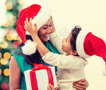 带礼品盒的幸福母亲和少女 女孩 树 圣诞节 帽子背景图片