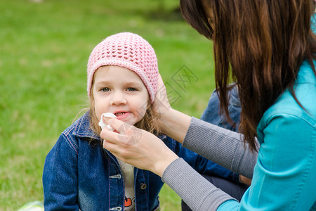 母亲在野餐时用餐巾纸女孩擦嘴背景图片