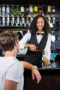 美丽的酒吧女招待倒酒杯啤酒背景图片