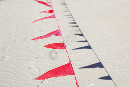 红色锦旗反对 beac 沙子的小红旗 有风的 彩旗 三角形的背景