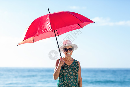 穿着雨伞的年长妇女 海 高级的 太阳帽背景图片