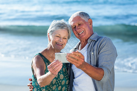 老年夫妇自拍 海滩 假期 支撑 屏幕 微笑背景图片