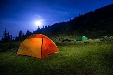 月亮睡觉两座彩色橙色和绿色露营帐篷 户外 辉光 月亮 假期背景