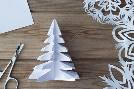 圣诞折纸木制桌上的手工造纸雪花和剪刀 老了 树 假期背景