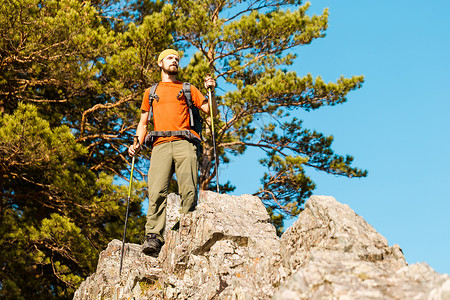 走还是留留着胡须的年轻男性正在穿越山区 旅游背包站在岩石山上 同时欣赏自然景观 在山区度过暑假 夏天 自由背景