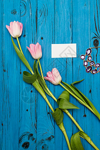 蓝色木板上的粉红色郁金香 空的 信 生日背景图片
