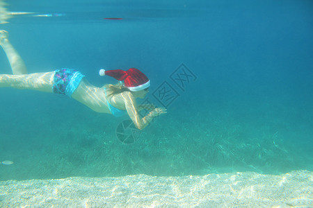 在水下游泳的圣塔帽女人 热带 圣诞节 女士 异国情调 太阳镜背景图片
