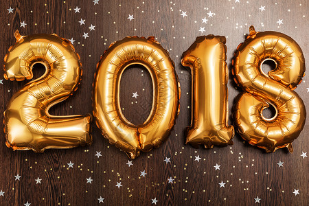 2018年 圣诞节 新年气球 黑色木质桌底有闪亮星的亮金金色气球 问候语 假期背景图片