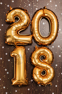 2018年 圣诞节 新年气球 黑色木质桌底有闪亮星的亮金金色气球 假期 明信片背景图片