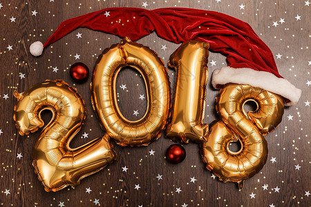 2018年 圣诞节 新年气球 黑色木质桌底有闪亮星的亮金金色气球 金属的背景图片