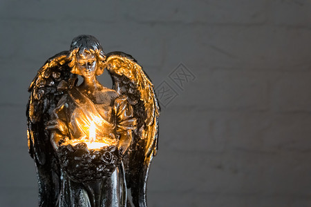 基督教火素材手持点燃的蜡烛 圣诞节和精神传统的银色天使雕像的特写背景