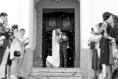 新婚夫妇在婚礼后离开教堂时亲吻 家人和朋友用肥皂泡淋浴庆祝他们的爱 破坏传统米浴的习俗 套装 教堂婚礼背景图片