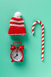 柔和的绿松石背景上的圣诞糖果手杖 时钟和帽子 冬季简约平躺 垂直的 顶视图 静物 等待假期 特写 顶视图背景图片